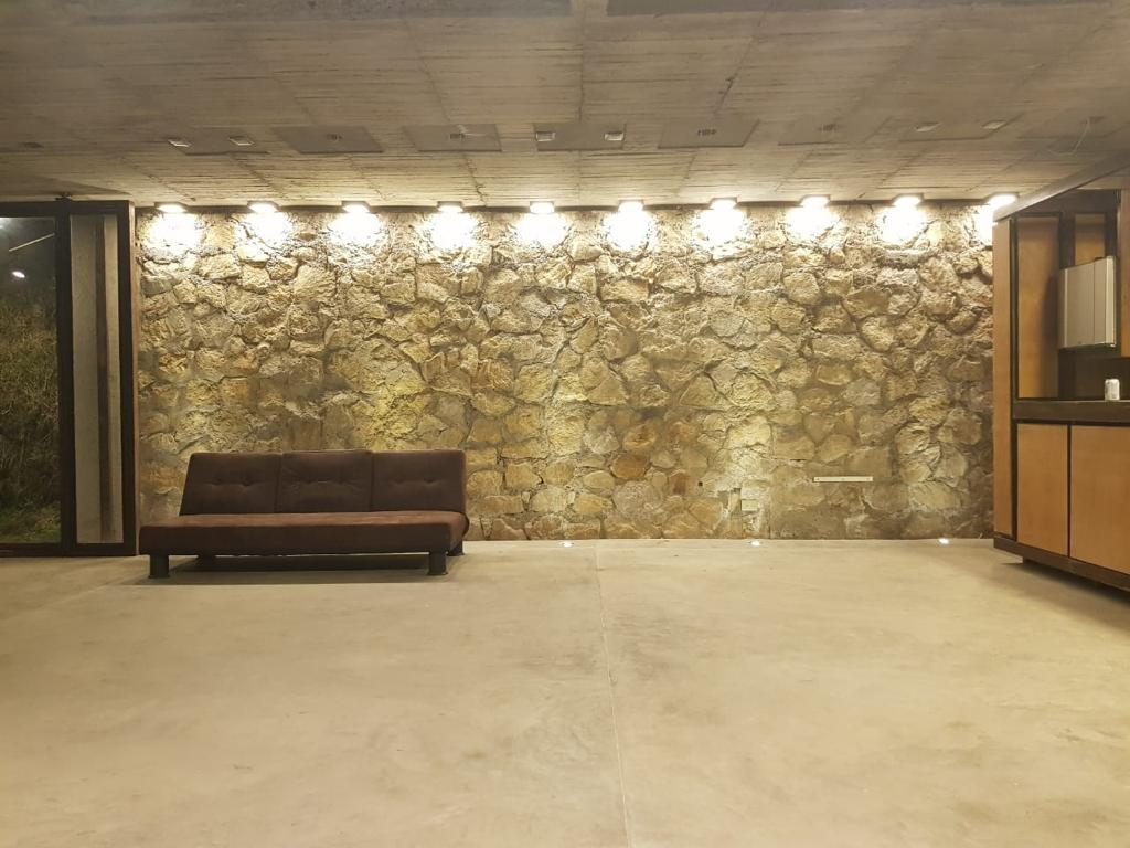 Salón con muro de piedra iluminado en Casa Lars